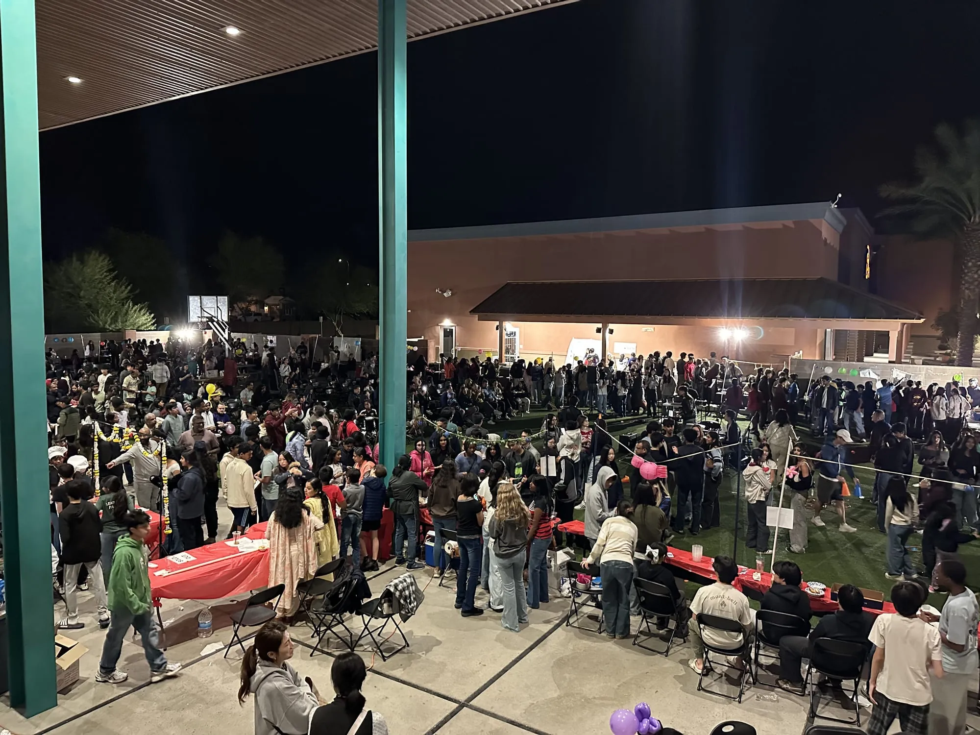 Crowds move between rows of red booth tables at night
