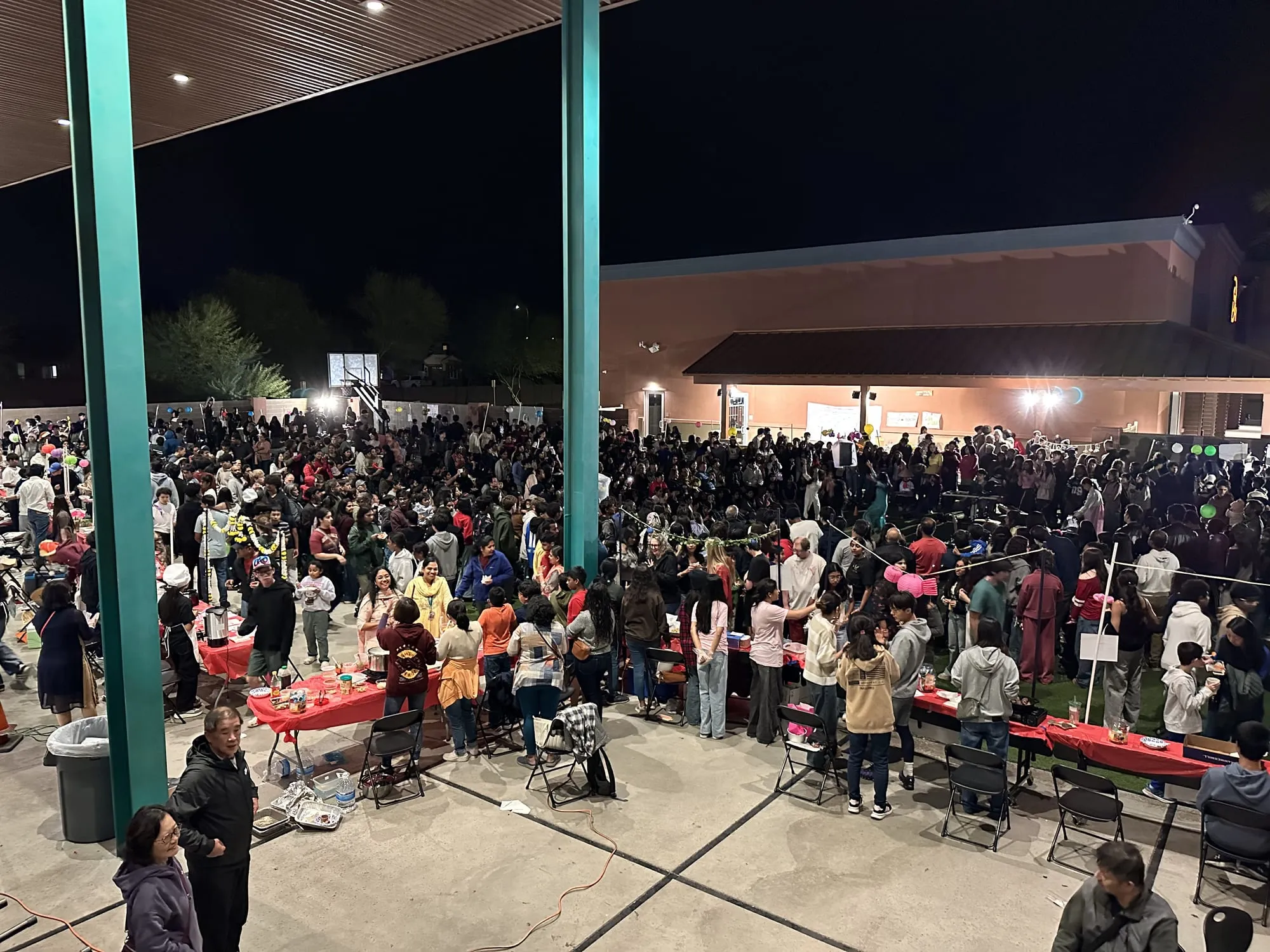 An overhead view of booth rows and crowds on the field at night
