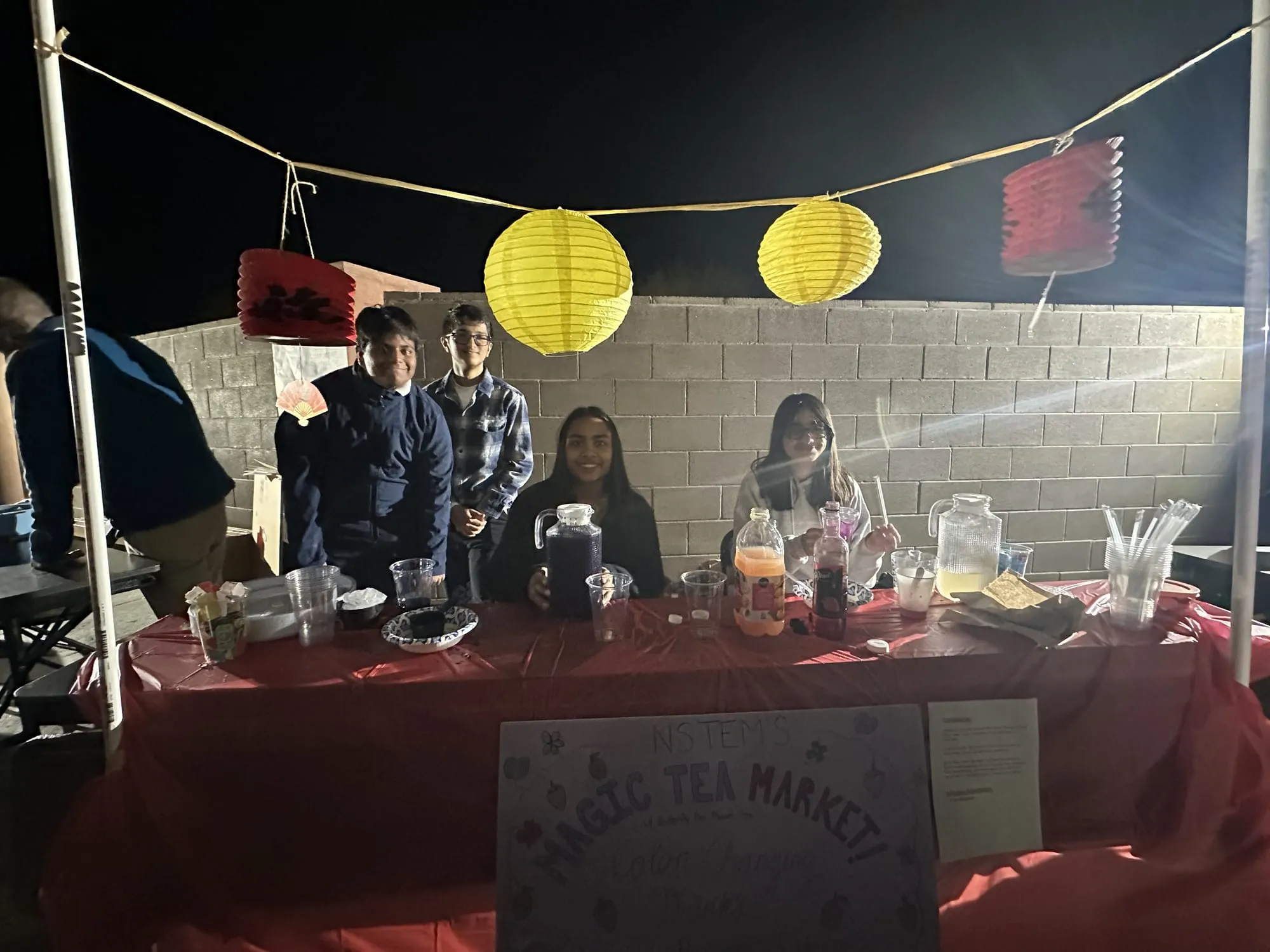 Students at a bubble tea booth under yellow and red lanterns at night