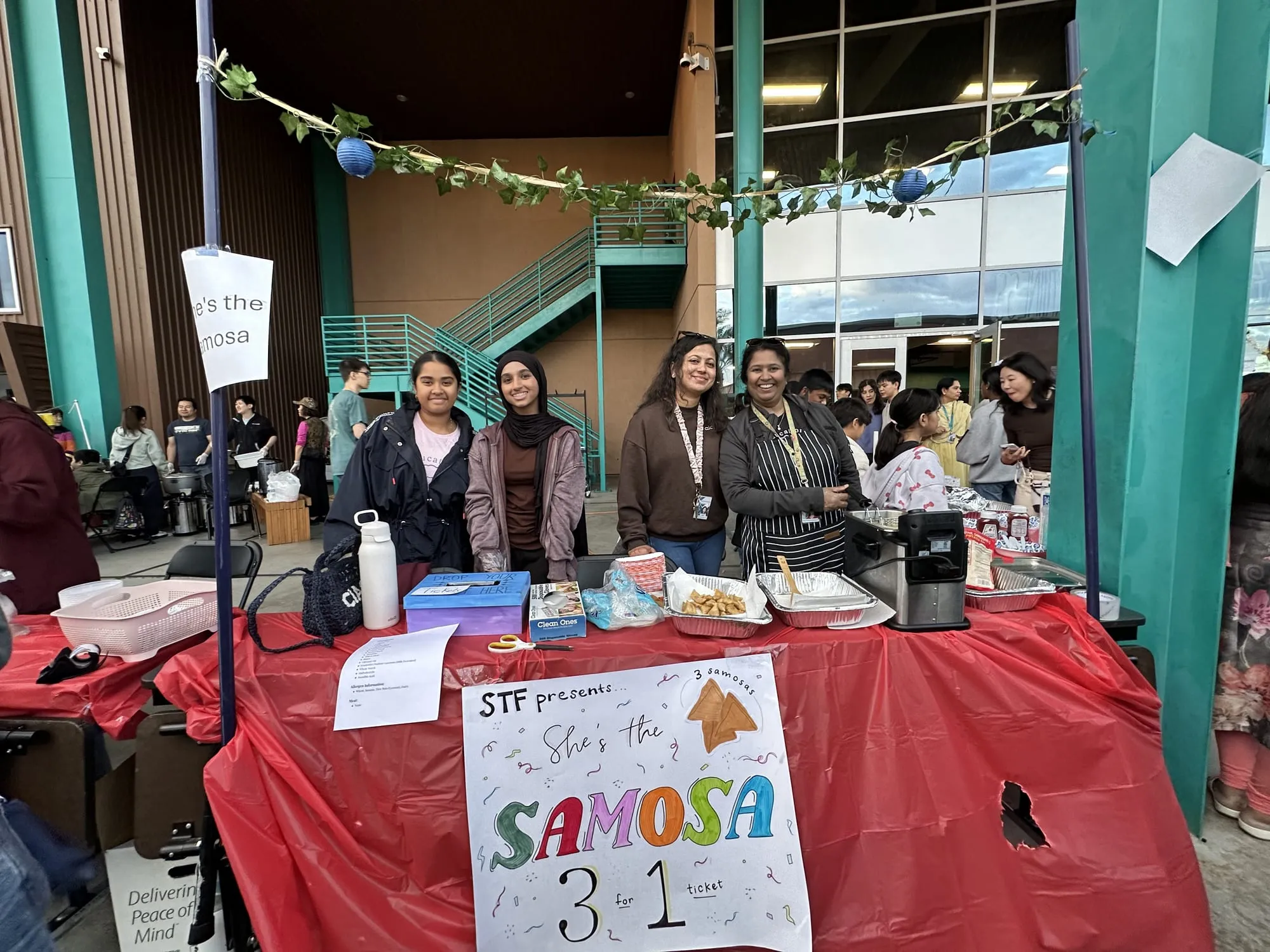 Club members and parents behind a samosa booth with a hand-drawn sign