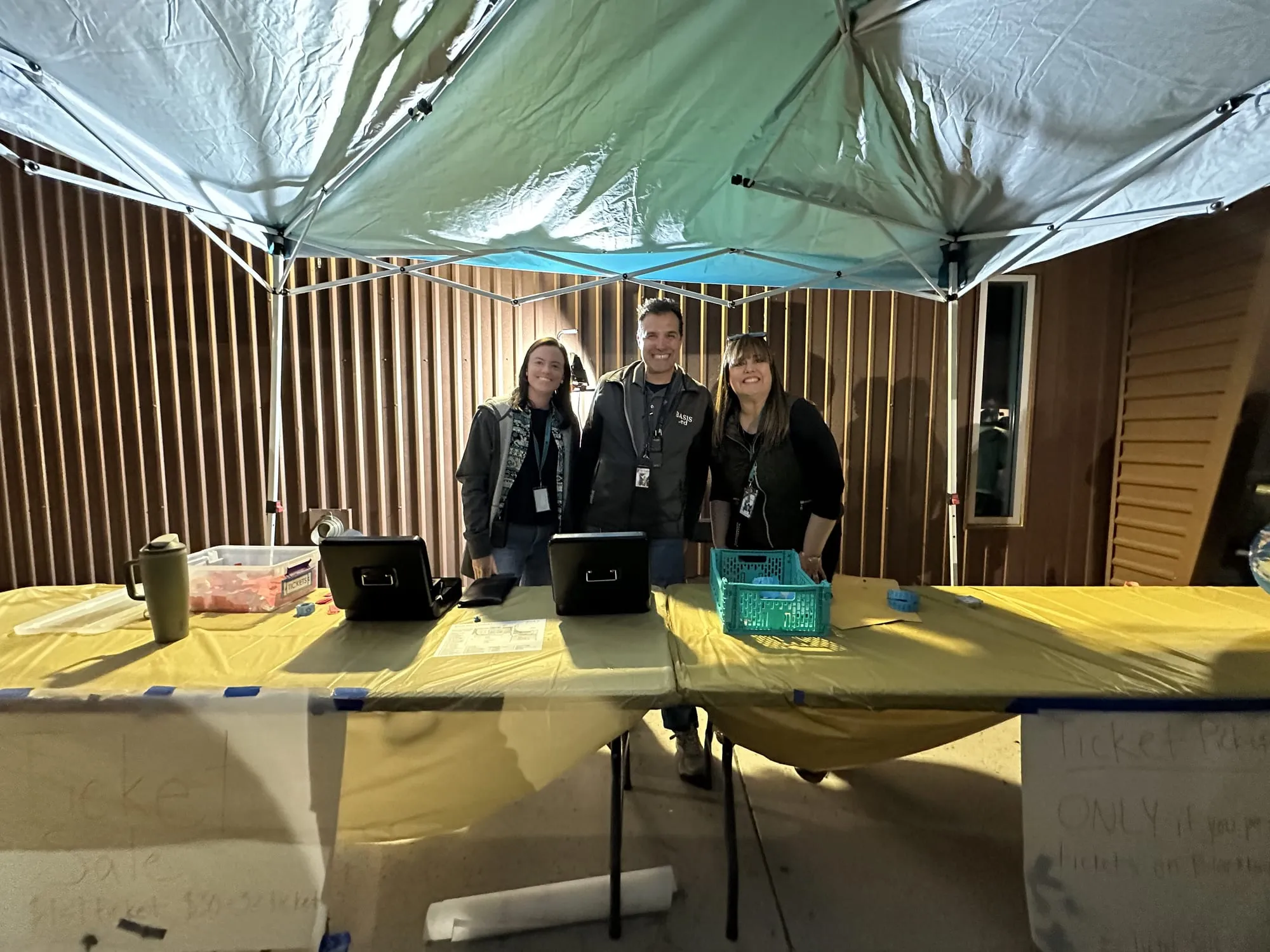 Teachers staffing the ticket table under a canopy